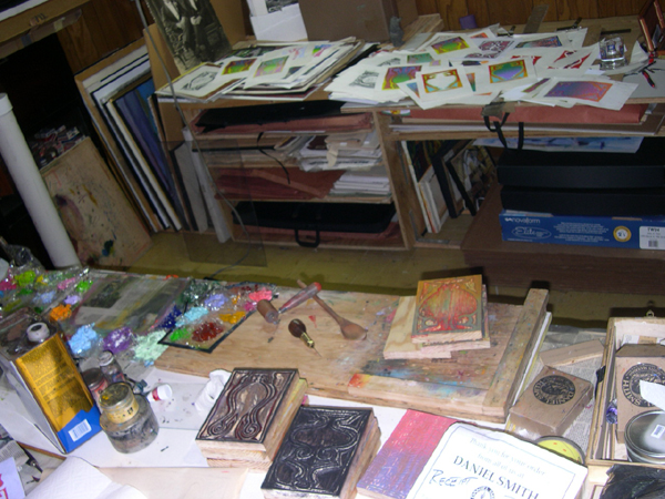 Work stations with tools and woodblocks in the foreground and print proofs in the background.
